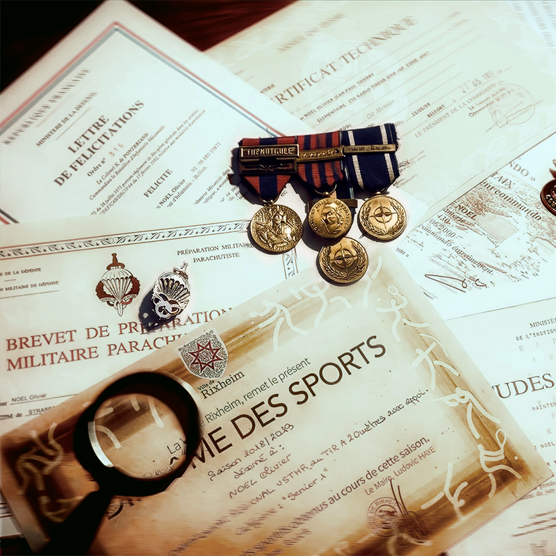Décorations et distinctions militaires d'Olivier Noël : médailles (OTAN, ex-Yougoslavie, Kosovo), brevet parachutiste, lettre de félicitations et récompense de tir.